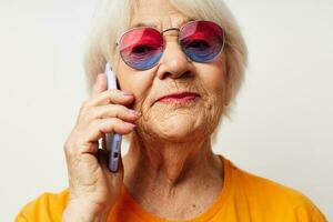 smiling elderly woman in casual t-shirt sunglasses talking on the phone close-up emotions photo