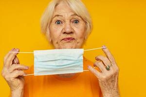 Portrait of an old friendly woman in yellow t-shirts in medical masks yellow background photo