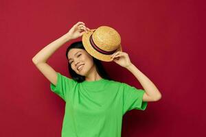 Portrait Asian beautiful young woman gestures with his hands with a hat in a green t-shirt red background unaltered photo