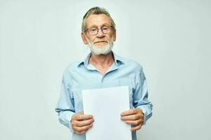 old man in a blue shirt and glasses a white sheet of paper light background photo