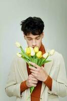 A young man in white jacket with a bouquet of yellow flowers elegant style background unaltered photo