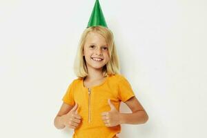 un niña con un verde gorra en su cabeza gestos con su manos foto