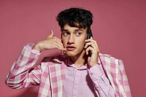 A young man fashionable talking on the phone pink blazer posing studio pink background unaltered photo