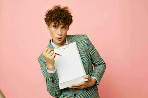 portrait of a young curly man in a business suit copy-space documents pink background unaltered photo