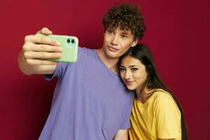 Man and woman in colorful T-shirts with a phone isolated background photo