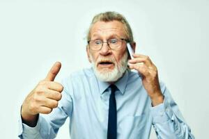 old man with phone in studio on white background shows thumb up photo