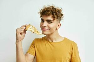 hermoso chico en un amarillo camiseta comiendo Pizza aislado antecedentes foto