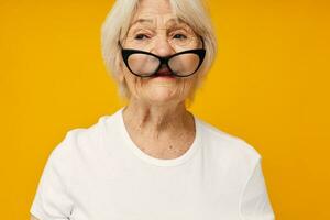 smiling elderly woman in a white t-shirt wears glasses isolated background photo