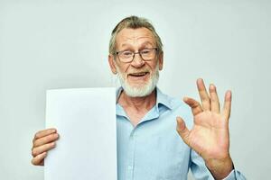Portrait elderly man holding a sheet of paper copy-space posing cropped view photo
