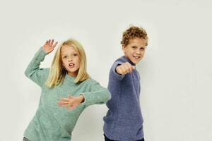 Portrait of cute children in multi-colored sweaters posing for fun light background photo