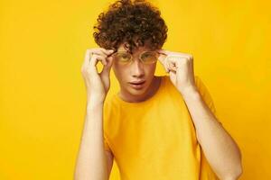 portrait of a young curly man Youth style glasses studio casual wear yellow background unaltered photo