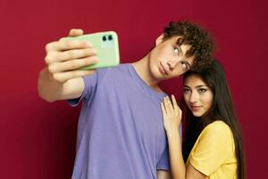 nice guy and girl in colorful T-shirts with a phone red background photo