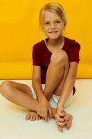 little girl sitting on the floor on a yellow background photo