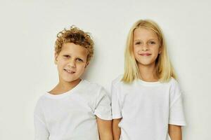 Photo of two children in white T-shirts are standing next to beige background