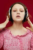 cheerful girl with headphones in a pink blouse music technology red background photo