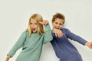 Portrait of cute children in multi-colored sweaters posing for fun light background photo