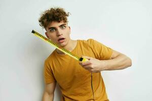 kinky guy measuring tape measure in yellow t-shirt light background photo