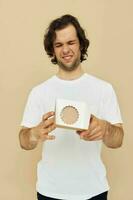 cheerful man in a white t-shirt with a cardboard box in his hands photo