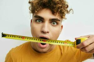 handsome guy measuring tape measure in yellow t-shirt Lifestyle unaltered photo