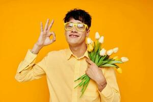 Photo of romantic young boyfriend with a fashionable hairstyle in yellow shirts with flowers yellow background unaltered