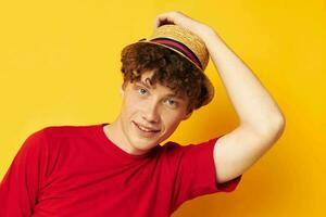 Young curly-haired man emotions red t-shirt hat studio yellow background unaltered photo