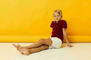 niña sentado en el piso posando amarillo antecedentes foto