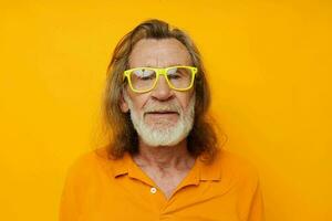 Senior grey-haired man yellow t-shirt and glasses posing yellow background photo