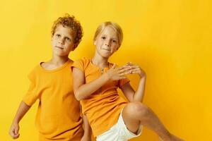 cheerful children in yellow t-shirts standing side by side childhood emotions yellow background unaltered photo