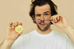 Attractive man in a white T-shirt with Bitcoin cryptocurrency beige background photo