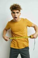 kinky guy measuring tape measure in yellow t-shirt light background photo