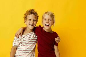 picture of positive boy and girl standing side by side posing childhood emotions yellow background photo