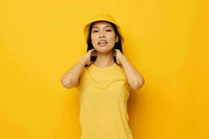 Charming young Asian woman wearing a yellow hat posing emotions yellow background unaltered photo