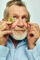 Portrait of happy senior man in a blue shirt bitcoins on the face cropped view photo