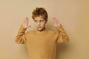 Cute little boy in a beige sweater posing fun childhood unaltered photo