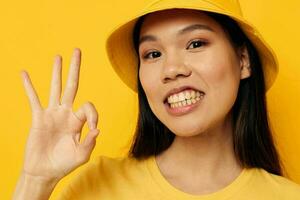woman with Asian appearance in a yellow t-shirt and hat posing emotions isolated background unaltered photo