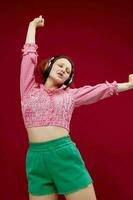 cheerful girl in a pink shirt listening to music on headphones unaltered photo