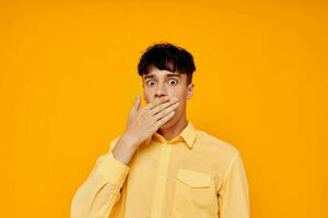 Cheerful young man in a yellow shirt gestures with his hands emotions photo