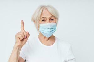 Portrait of an old friendly woman health lifestyle medical mask treatment light background photo