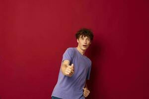 A young man in purple t-shirts medical mask in hands safety isolated background unaltered photo