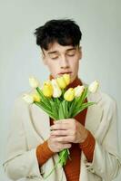 pretty man in white jacket with a bouquet of yellow flowers elegant style model studio photo