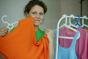 portrait of a young woman ironing clothes on a hanger wardrobe light background unaltered photo