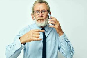 Photo of retired old man in a shirt with a tie talking on the phone isolated background