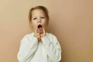 pequeño niña en blanco suéter posando mano gestos infancia inalterado foto