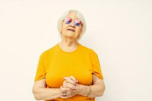 retrato de un antiguo simpático mujer en casual camiseta Gafas de sol ligero antecedentes foto