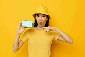 pretty brunette in a yellow T-shirt and a hat with a gift studio model unaltered photo