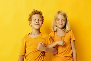 dos alegre niños casual vestir juegos divertido juntos posando en de colores antecedentes foto