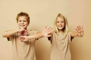 retrato de linda niños en beige camisetas posando para divertido aislado antecedentes foto