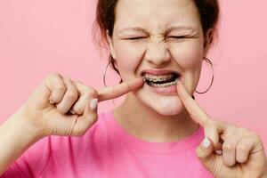 woman in pink t-shirt braces posing pink background photo