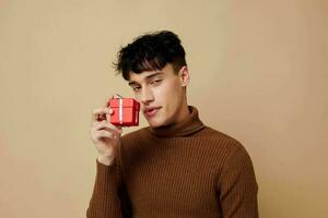 A young man posing in brown sweater self confidence fashion light background unaltered photo