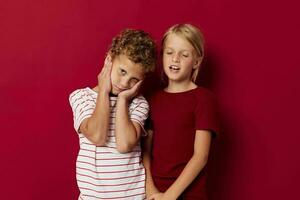 Cute stylish kids emotions stand side by side in everyday clothes red background photo